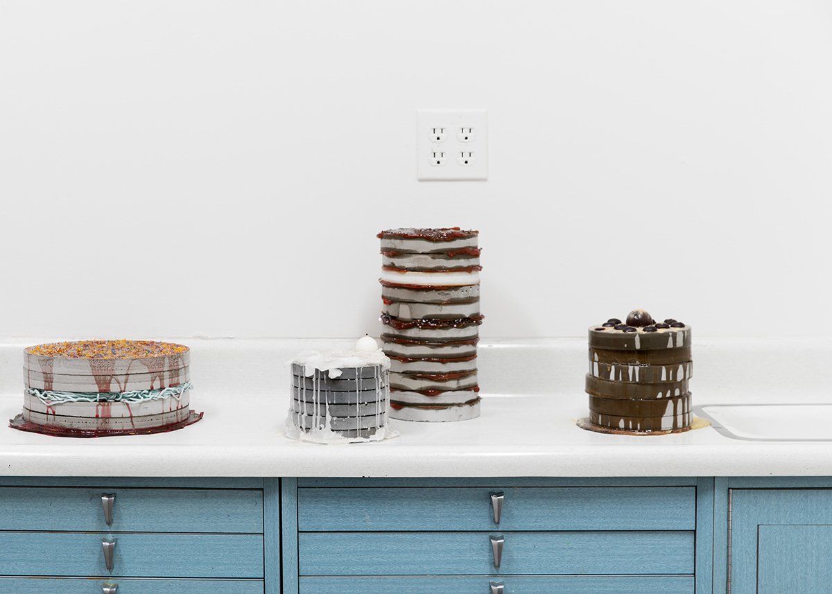 Cat Quattrochiocchi, Ode to Cakes, 2017-18. From left to right: Stack I, concrete, yarn, gelatin and plastic, 10x10x4.5in. Stack II, concrete, wax, coconut syrup, 6x6x4.75in. Stack III, concrete, grease, and electronic bits, 6.5x6.5x11.5in. Stack IV, concrete, urethane, gelatin, and powdered orange peel, 6.5x6.5x7.5in. Photo by Joel Tsui.