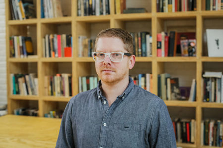Full color headshot of James McAnally standing in front of bookshelves