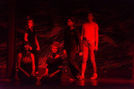 The five commissioned dancers for This is why we can't have nice things are young white women who are bathed in red light. Two are in all black street clothing, kneeling, and three are standing behind them, two in all-black clothing, and one, on the right, in all white gym clothes.